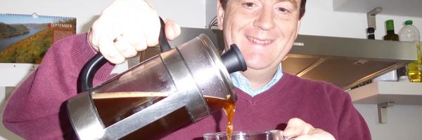Gunnar Bach lächelt und schenkt Kaffee aus einer French Press-Kanne in eine Tasse.